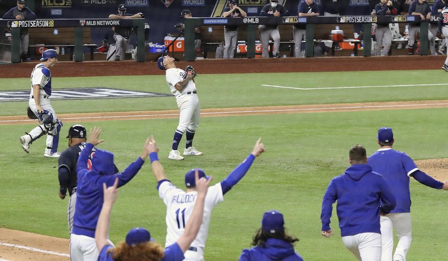 The Atlanta Braves dugout looks on as the Los Angeles Dodgers begin to celebrate their 4-3 victory in Game 7 of a baseball National League Championship Series, Sunday, Oct. 18, 2020, in Arlington, Texas. (Curtis Compton/Atlanta Journal-Constitution via AP)