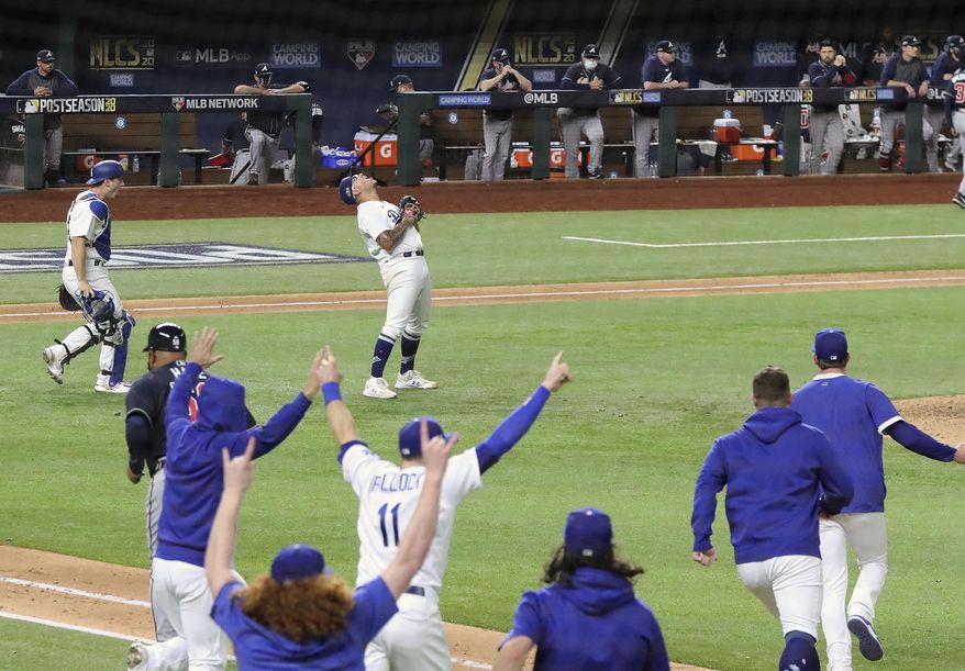The Atlanta Braves dugout looks on as the Los Angeles Dodgers begin to celebrate their 4-3 victory in Game 7 of a baseball National League Championship Series, Sunday, Oct. 18, 2020, in Arlington, Texas. (Curtis Compton/Atlanta Journal-Constitution via AP)