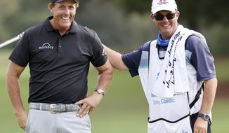 Winner Phil Mickelson gets a pat on the back from Jeff Johnson, the caddie for Retief Goosen, during final round play in the Dominion Energy Charity Classic at the Country Club of Virginia in Richmond, Virginia, on Sunday, October 18, 2020. Mickelson finished 3 strokes ahead of Canada&#39;s Mike Weir.  (Joe Mahoney/Richmond Times-Dispatch via AP)