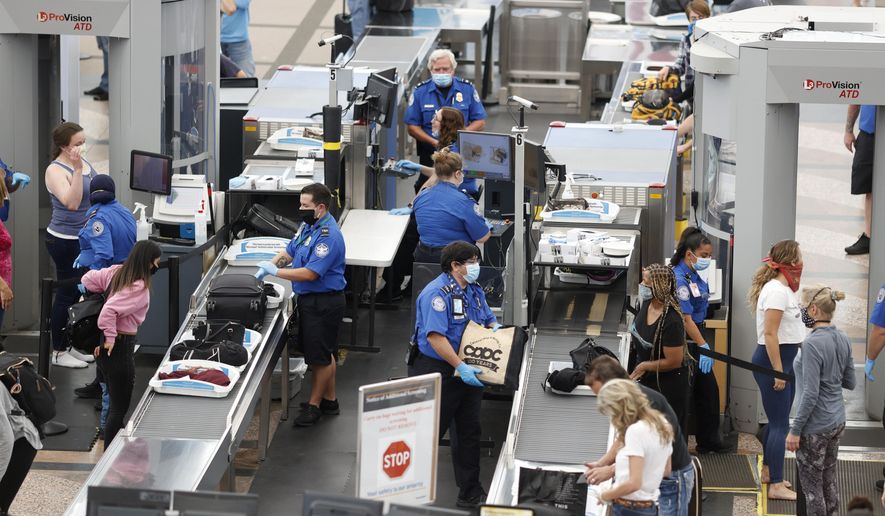 In this June 10, 2020, file photo, Transportation Security Administration agents process passengers at the south security checkpoint at Denver International Airport in Denver, as travelers deal with the effects of the coronavirus. (AP Photo/David Zalubowski, File)