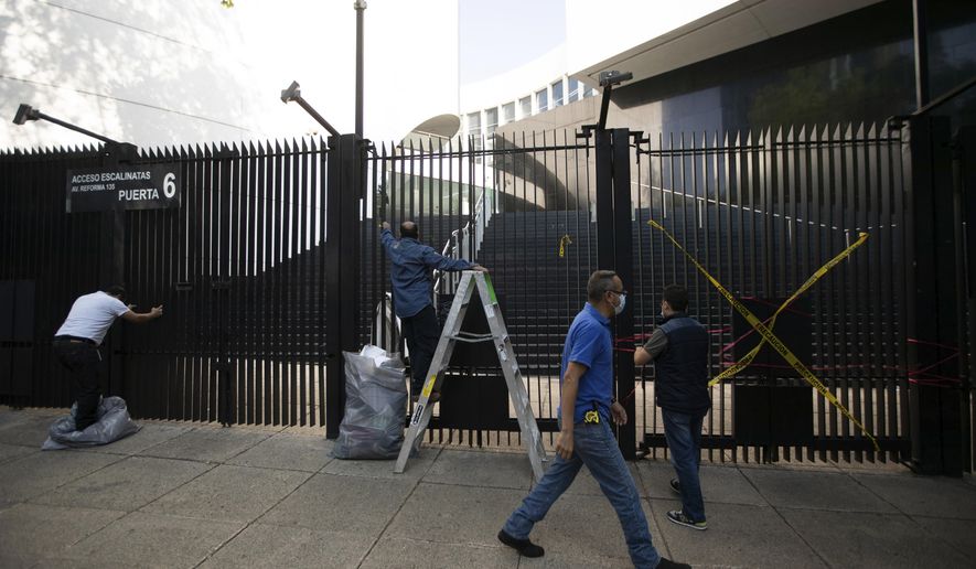 Senate workers remove posters and ribbons placed by demonstrators protesting against Mexican President Andres Manuel Lopez Obrador’s effort to eliminate trust funds which he says are sources of corruption, at an entrance to the Senate in Mexico City, Wednesday, Oct. 21, 2020. The Senate passed various laws on Wednesday eliminating over 100 trusts which finance everything from science to movie productions to disaster relief. (AP Photo/Fernando Llano)