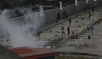 Protesters run away as police officers use teargas to disperse people demonstrating against police brutality in Lagos, Nigeria, Wednesday, Oct. 21, 2020. After 13 days of protests against alleged police brutality, authorities have imposed a 24-hour curfew in Lagos, Nigeria&#39;s largest city, as moves are made to stop growing violence. ( AP Photo/Sunday Alamba)