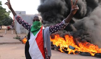 A demonstrators gives the victory sign at a protest, in Khartoum, Sudan, Wednesday, Oct. 21, 2020. Protesters have taken to the streets in the capital and across the country over dire living conditions and a deadly crackdown on demonstrators in the east earlier this month. Sudan is currently ruled by a joint civilian-military government, following the popular uprising that toppled longtime autocrat Omar al-Bashir last year. (AP Photo/Marwan Ali)