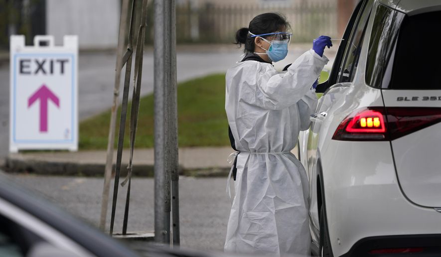Medical personnel prepare to administer a COVID-19 swab at a drive-through testing site in Lawrence, N.Y., Wednesday, Oct. 21, 2020. The rate of COVID-19 infections has risen enough in New Jersey, Pennsylvania and Connecticut to require those states&#x27; residents to quarantine if they travel to New York, but Gov. Andrew Cuomo says New York won&#x27;t enforce the rules against those residents. (AP Photo/Seth Wenig)
