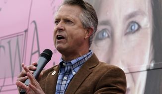 U.S. Rep. Roger Marshall, R-Kan., talks to the crowd in front of photo of Supreme Court nominee Amy Coney Barrett while attending a Concerned Women for America event outside a gun store in Kansas City, Kan. Wednesday, Oct. 21, 2020. Marshall is facing stiff competition from state Sen. Barbara Bollier in the race to fill an open Senate seat in Kansas. (AP Photo/Charlie Riedel)