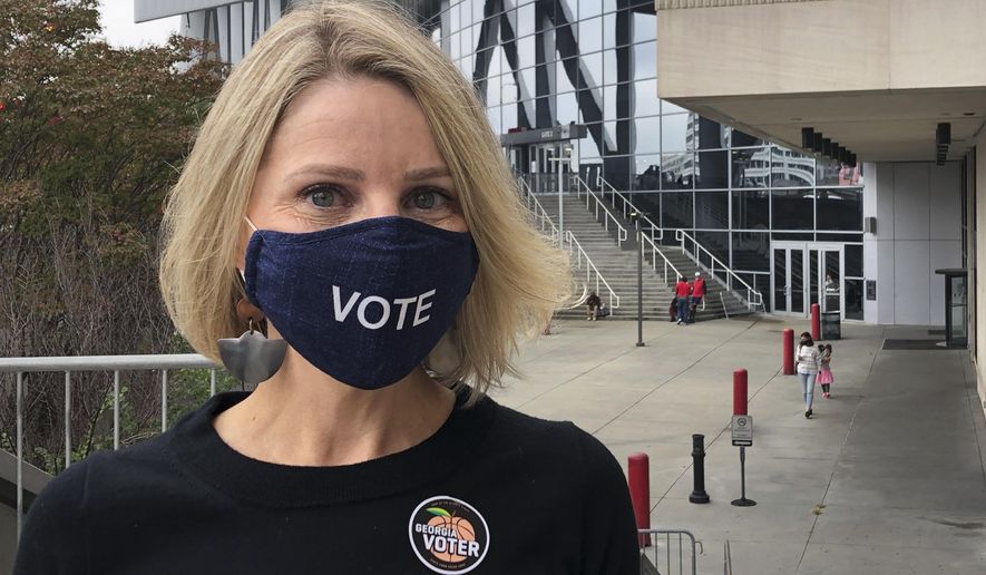 Jen Cox poses for a photo on Thursday, Oct. 15, 2020, after voting early at State Farm Arena in downtown Atlanta. The arena, where the NBA's Atlanta Hawks play, is one of many professional sports venues around the country that has opened its doors for voting or other election-related activities. With dozens of voting machines and ample space for social distancing, they provide a safe and efficient way to vote during the ongoing coronavirus pandemic. (AP Photo/Kate Brumback)