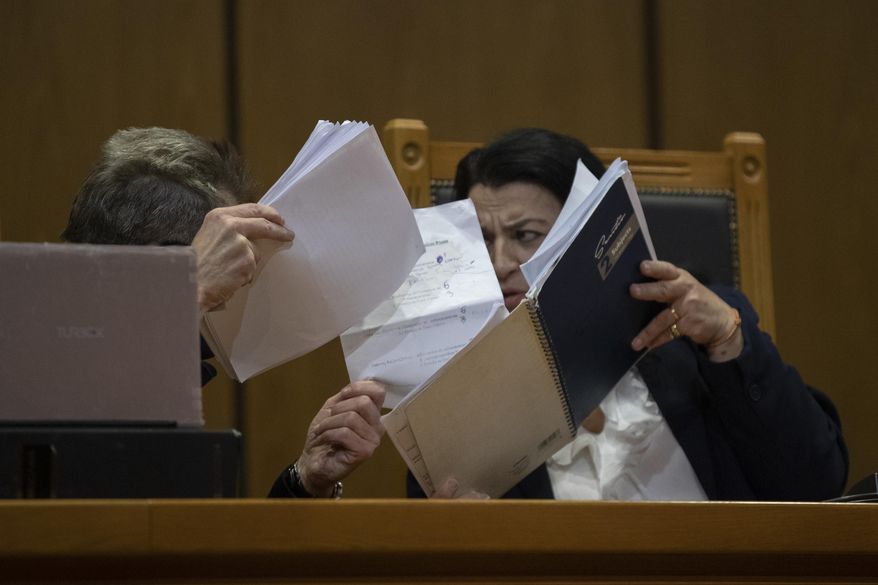 Presiding judge Maria Lepenioti consults a fellow judge as she reads the sentences during the Golden Dawn trial, in Athens, Thursday, Oct. 22, 2020. The court has sentenced the leadership of Greece's extreme-right Golden Dawn party to 13 years in prison, imposing the near-maximum penalty for running a criminal organization blamed for numerous violent hate crimes. The landmark ruling follows a five-year trial of dozens of top officials, members, and supporters of the organization founded as a Neo-Nazi group in the 1980s, that rose to become Greece's third-largest political party during a major financial crisis in the previous decade. (AP Photo/Petros Giannakouris)