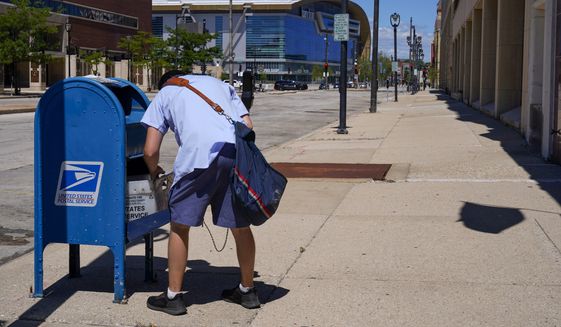 In this Aug. 18, 2020, file photo, a postal worker empties a box near the Fiserv Forum in Milwaukee. U.S. Postal Service records show delivery delays have persisted across the country as millions of Americans began voting by mail, raising the possibility of ballots being rejected because they arrive too late. Parts of the politically coveted battleground states of Wisconsin, Michigan, Pennsylvania and Ohio fell short of delivery goals by wide margins as the agency struggles to regain its footing after a tumultuous summer. (AP Photo/Morry Gash) **FILE**