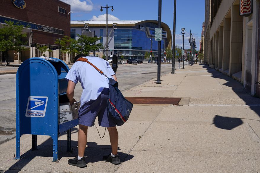In this Aug. 18, 2020, file photo, a postal worker empties a box near the Fiserv Forum in Milwaukee. U.S. Postal Service records show delivery delays have persisted across the country as millions of Americans began voting by mail, raising the possibility of ballots being rejected because they arrive too late. Parts of the politically coveted battleground states of Wisconsin, Michigan, Pennsylvania and Ohio fell short of delivery goals by wide margins as the agency struggles to regain its footing after a tumultuous summer. (AP Photo/Morry Gash) **FILE**