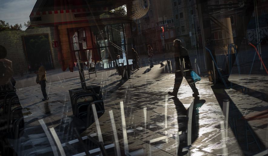 People walk past a restaurant closed due to the sharp resurgence of coronavirus cases, in Barcelona, Spain, Friday, Oct. 23, 2020. Spain has reported 1 million confirmed infections — the highest number in Western Europe — and at least 34,000 deaths from COVID-19, although experts say the number is much higher since many cases were missed because of testing shortages and other problems. (AP Photo/Emilio Morenatti)