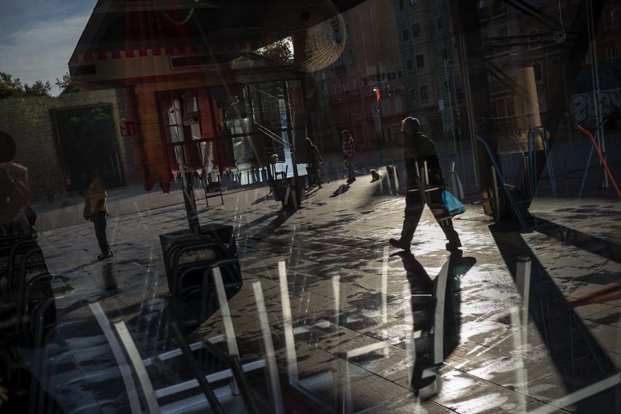 People walk past a restaurant closed due to the sharp resurgence of coronavirus cases, in Barcelona, Spain, Friday, Oct. 23, 2020. Spain has reported 1 million confirmed infections — the highest number in Western Europe — and at least 34,000 deaths from COVID-19, although experts say the number is much higher since many cases were missed because of testing shortages and other problems. (AP Photo/Emilio Morenatti)