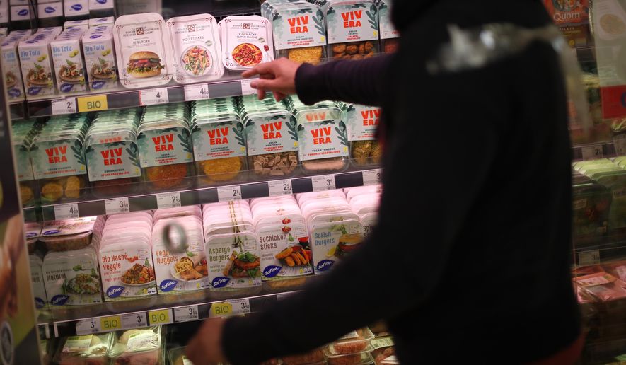 A store clerk shows plant based products at a supermarket chain in Brussels, Friday, Oct. 23, 2020. European lawmakers rejected Friday proposals that could have prevented plant-based products without meat from being labeled sausages or burgers. Following the votes on agricultural products at the European Parliament, the so-called veggie burgers, soy steaks and vegan sausages can continue to be sold as such in restaurants and shops across the union. (AP Photo/Francisco Seco)