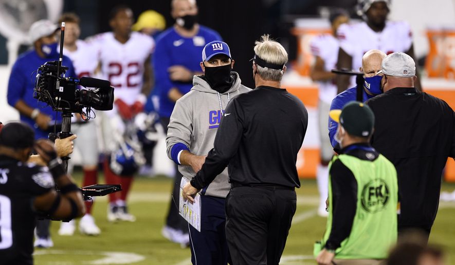 New York Giants head coach Joe Judge, left, and Philadelphia Eagles head coach Doug Pederson meet after an NFL football game, Thursday, Oct. 22, 2020, in Philadelphia. (AP Photo/Derik Hamilton)