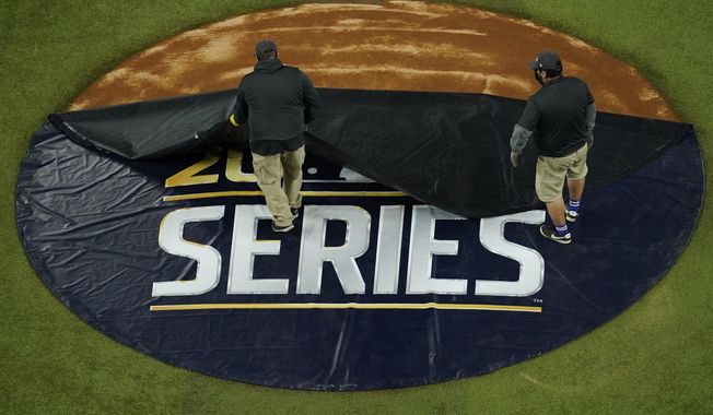 Members of the grounds crew uncover the pitcher&#x27;s mound before Game 3 of the baseball World Series between the Los Angeles Dodgers and the Tampa Bay Rays Friday, Oct. 23, 2020, in Arlington, Texas. (AP Photo/David J. Phillip)