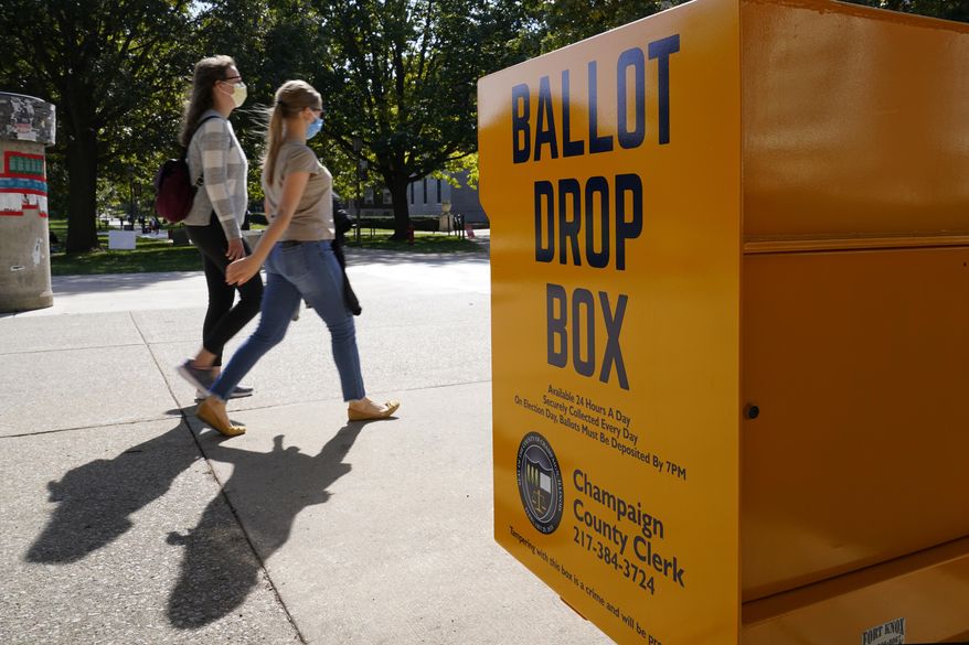 In this Oct. 6, 2020, photo, University of Illinois students walk past a mail-in ballot drop box that sits on the northwest corner of the university's Quad in Urbana, Ill. (AP Photo/Charles Rex Arbogast) ** FILE **