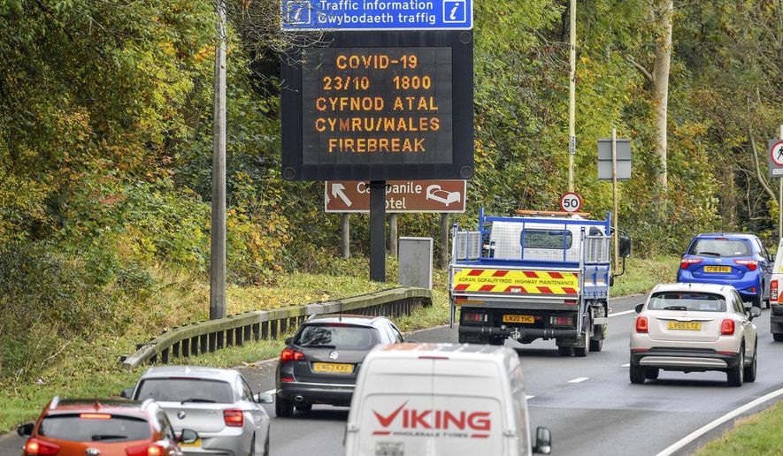 A matrix sign on the A48(M) heading towards Cardiff informing motorists to Wales entering a &amp;quot;firebreak&amp;quot; lockdown, Friday, Oct. 23, 2020. A police force in England says it will try to stop people from leaving Wales, which has started a 17-day lockdown to slow the spread of COVID-19. The Gloucestershire Constabulary says it will patrol routes from Wales and pull over drivers they believe are making long journeys. Travelers without a good excuse will be asked to turn around. (Ben Birchall/PA via AP)