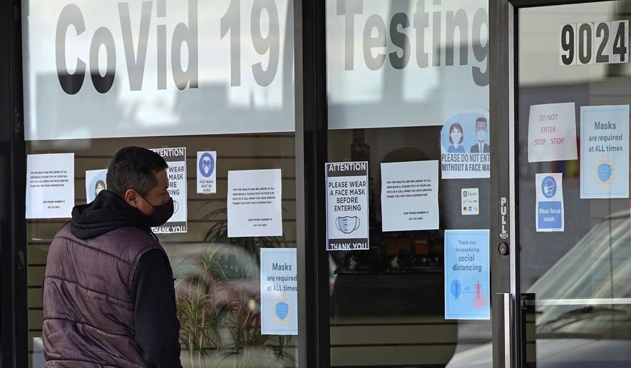 A man wears a mask as he looks at information signs at Exam Corp Lab for COVID-19 testing in Niles, Ill., Wednesday, Oct. 21, 2020. (AP Photo/Nam Y. Huh)