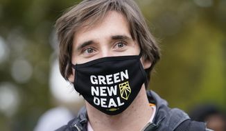 A volunteer working for U.S. Rep. Alexandria Ocasio-Cortez, (D-N.Y.), wears a Green New Deal mask as he waits in line to meet the New York congresswoman at a Pledge to Vote event, Sunday, Oct. 25, 2020, in the Bronx borough of New York. Early voting ahead of the Nov. 3 general election continued for the second day in New York state. (AP Photo/Kathy Willens)