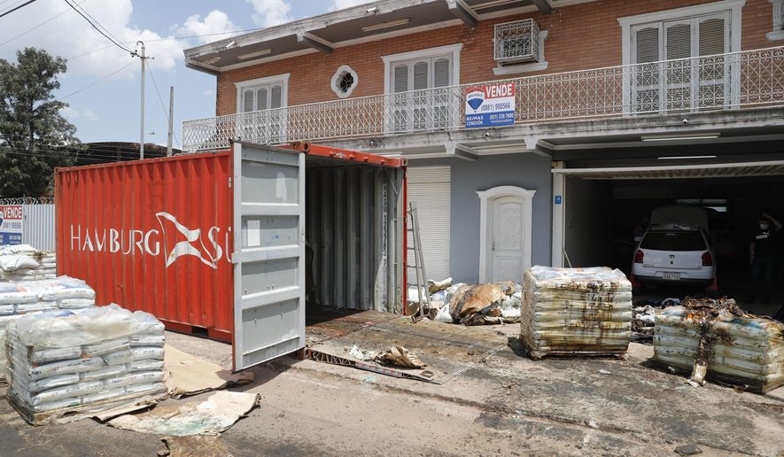 Human remains cover bags removed from a container in a street outside an office building in Asuncion, Paraguay, Friday, Oct. 23, 2020. According to prosecutor Marcelo Saldivar, seven bodies were found in the container, holding fertilizer, that left Serbia in July and arrived at Paraguay's Terport de Villeta port in October. (AP Photo/Jorge Saenz)