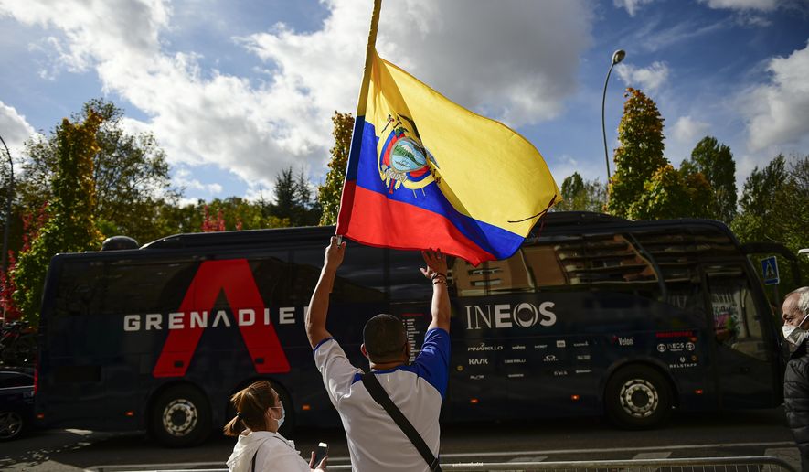 Ecuadorian fans of Richard Carapaz, waves national flag in front of the Ineos's team bus before the second stage of La Vuelta between Pamplona and Lekunberri, in Pamplona, northern Spain, Wednesday, Oct. 21, 2020. (AP Photo/Alvaro Barrientos)