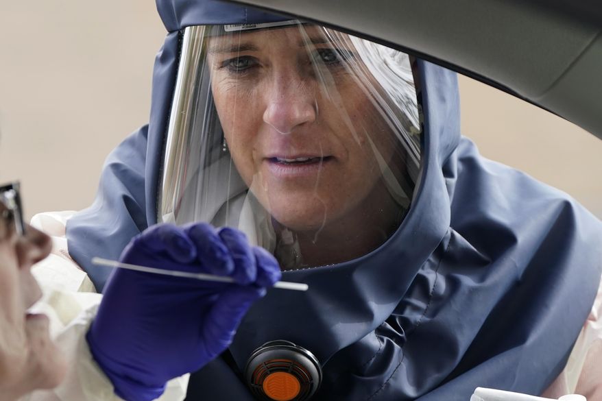 In this Friday, Oct. 23, 2020, photo, Salt Lake County Health Department public health nurse Lee Cherie Booth performs a coronavirus test outside the Salt Lake County Health Department in Salt Lake City. (AP Photo/Rick Bowmer) **FILE**