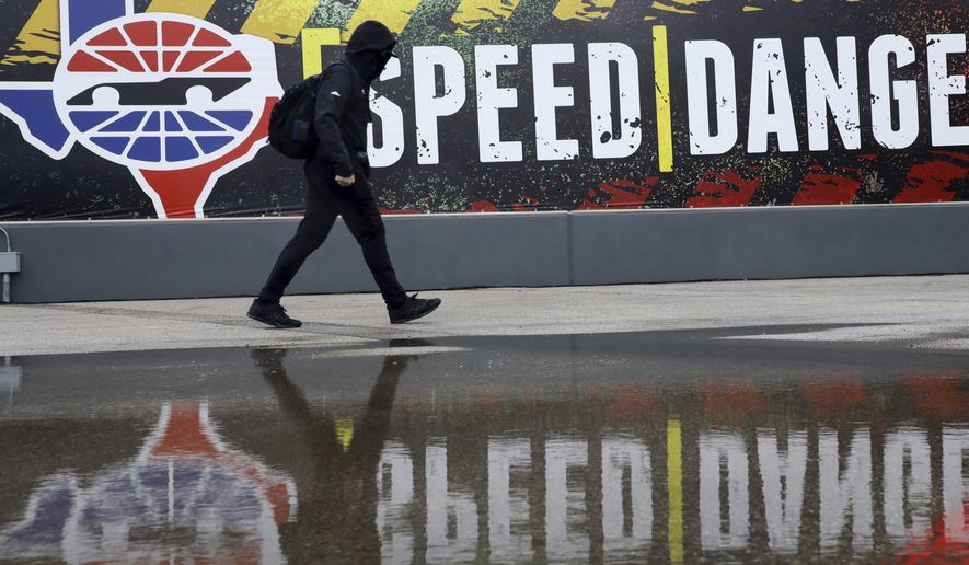A pit crew member walks past the media center as crews wait out a delay at a NASCAR Cup Series auto race after morning rain prevented the 9 a.m. rescheduled start at Texas Motor Speedway in Fort Worth, Texas, Monday, Oct. 26, 2020. (AP Photo/Richard W. Rodriguez)
