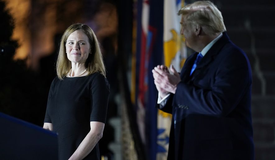 President Donald Trump looks toward Amy Coney Barrett, before Supreme Court Justice Clarence Thomas administers the Constitutional Oath to her on the South Lawn of the White House in Washington, Monday, Oct. 26, 2020, after Barrett was confirmed by the Senate earlier in the evening. (AP Photo/Patrick Semansky)