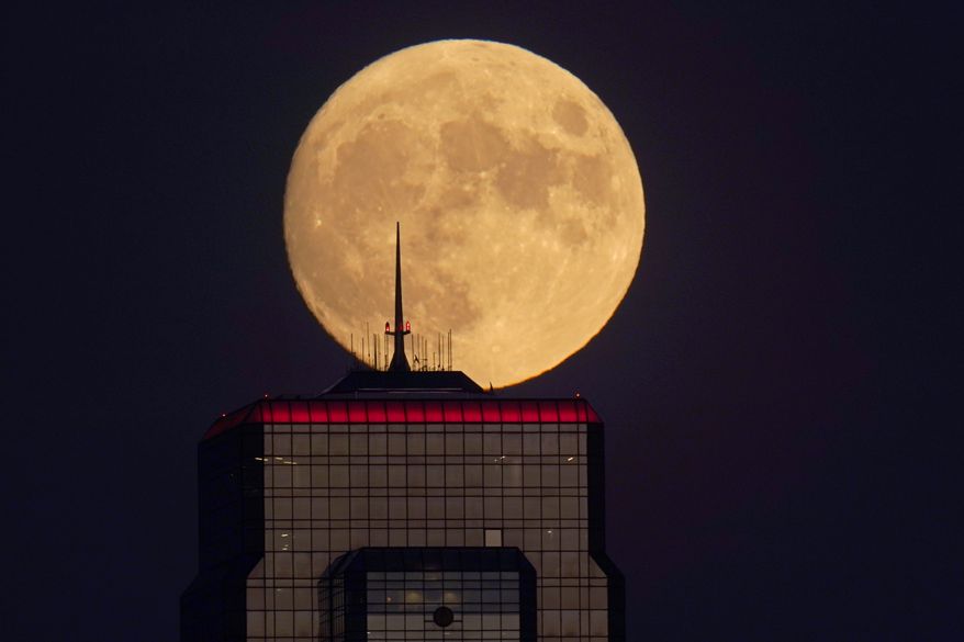 In this Wednesday, Sept. 30, 2020, file photo, a nearly full moon rises, with an office building in the foreground, in downtown Kansas City, Mo. The moons shadowed, frigid nooks and crannies may hold frozen water in more places and in larger quantities than previously suspected, good news for astronauts at future lunar bases who could tap into these resources for drinking and making rocket fuel, scientists reported Monday, Oct. 26, 2020. (AP Photo/Charlie Riedel, File)