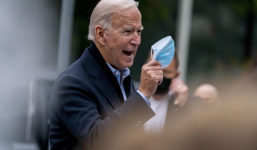 Democratic presidential candidate former Vice President Joe Biden holds up his face mask as he speaks to members of the media outside a voter service center, Monday, Oct. 26, 2020, in Chester, Pa. (AP Photo/Andrew Harnik)