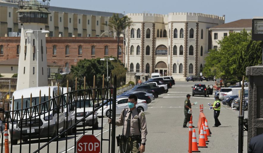FILE - In this July 9, 2020, file photo, a correctional officer closes the main gate at San Quentin State Prison in San Quentin, Calif. California prison officials did a poor job requiring inmates and staff to wear masks to slow the spread of the coronavirus, and even "perplexingly loosened" their policy just as cases were spiking, the state's inspector general said Monday, Oct. 26, 2020. (AP Photo/Eric Risberg, File)