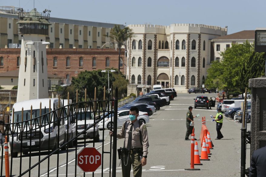 FILE - In this July 9, 2020, file photo, a correctional officer closes the main gate at San Quentin State Prison in San Quentin, Calif. California prison officials did a poor job requiring inmates and staff to wear masks to slow the spread of the coronavirus, and even "perplexingly loosened" their policy just as cases were spiking, the state's inspector general said Monday, Oct. 26, 2020. (AP Photo/Eric Risberg, File)