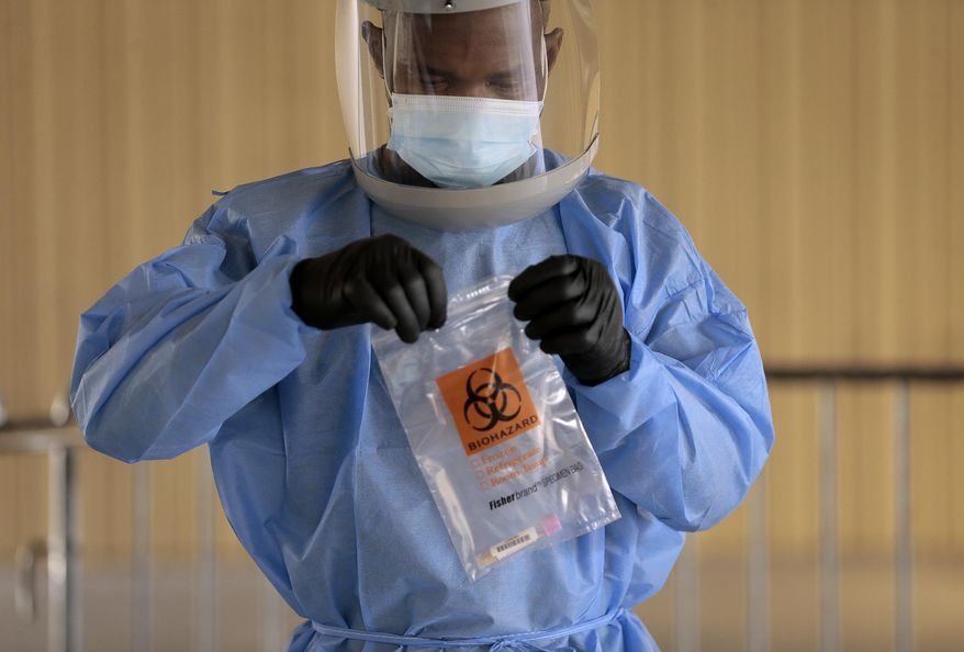Divine Ayong seals a test in a biohazard bag after collecting a sample Monday, Sept. 21, 2020, at The University of Texas at El Paso's Fox Fine Arts building in El Paso, Texas. Deaths per day from the coronavirus in the U.S. are on the rise again, just as health experts had feared, and cases are climbing in nearly every single state. In El Paso, authorities instructed people to stay home for two weeks and imposed a 10-p.m.-to-5-a.m. curfew because of a surge that has overwhelmed hospitals. (Mark Lambie/The El Paso Times via AP)