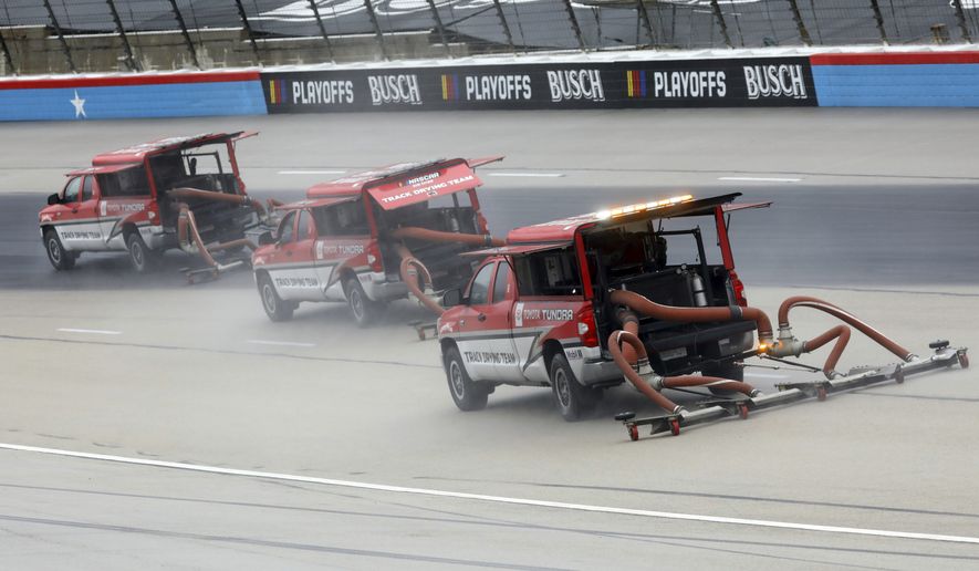 Drying trucks continue to prepare the track for a possible NASCAR Cup Series auto race at Texas Motor Speedway in Fort Worth, Texas, Tuesday, Oct. 27, 2020. The race was stopped on Sunday because of drizzle and misty conditions that allowed drivers to complete just 52 of 334 laps. Another 115 laps have to be completed to get to the halfway mark of 167 laps that would make Texas an official race. (AP Photo/Richard W. Rodriguez)