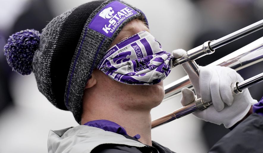A member of the Kansas State marching band plays the trombone while wearing a face mask during the second half of an NCAA football game against Kansas Saturday, Oct. 24, 2020, in Manhattan, Kan. (AP Photo/Charlie Riedel)