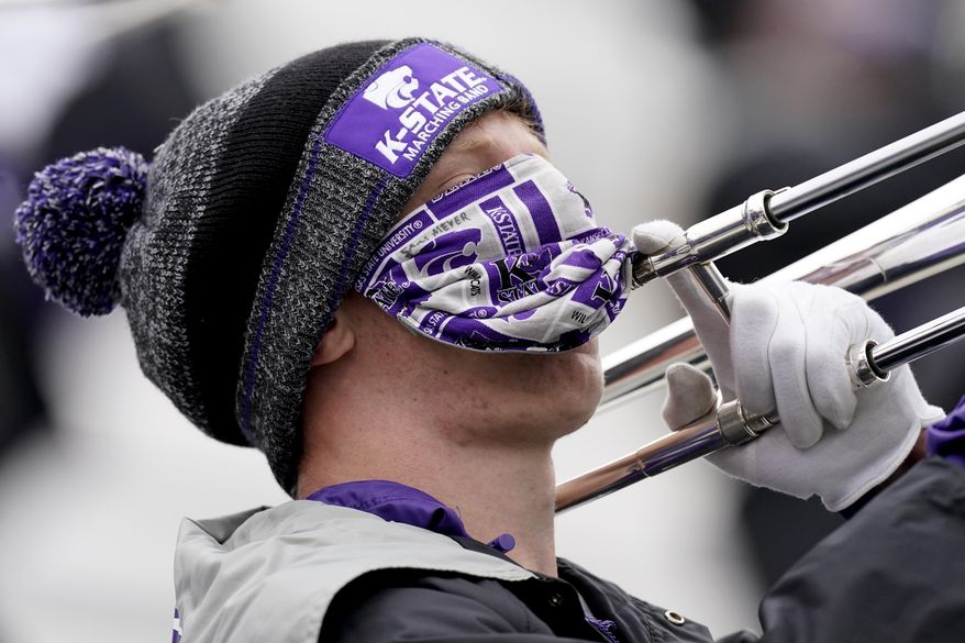 A member of the Kansas State marching band plays the trombone while wearing a face mask during the second half of an NCAA football game against Kansas Saturday, Oct. 24, 2020, in Manhattan, Kan. (AP Photo/Charlie Riedel)