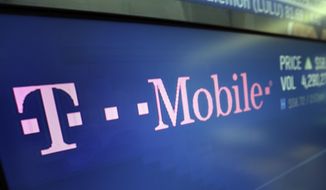 In this Feb. 14, 2018, photo, the T-Mobile logo appears on a screen at the Nasdaq MarketSite in New York. (AP Photo/Richard Drew) **FILE**