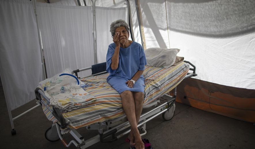 Nancy Rodriguez, a 76-yar-old COVID-19 patient, wipes tears as she explains her battle with the virus under a tent for patients who will be discharged from the Peréz de León II Hospital, a public hospital where Doctors Without Borders operates in the Petare neighborhood of Caracas, Venezuela, Monday, Sept. 22, 2020. Venezuela&#39;s count of roughly 800 COVID-19 deaths among its more than 90,000 cases is likely an undercount, as many are fearful of the broken health care system and choose to stay home. (AP Photo/Ariana Cubillos)