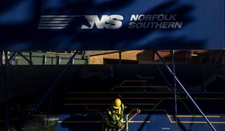 FILE- In this Oct. 23, 2019 file photo, a worker sweeps a sidewalk outside the construction site for the new corporate headquarters of Norfolk Southern Railway, in Atlanta. Norfolk Southern’s third-quarter profit fell more than 13% as the railroad delivered fewer shipments and the results were weighed down by a one-time charge. The railroad said Wednesday, Oct. 28, 2020, that it earned $569 million, or $2.22 per share. (AP Photo/David Goldman, File)