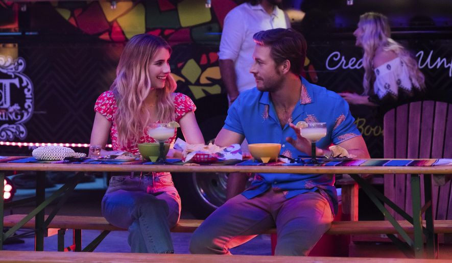 This image released by Netflix shows Emma Roberts and Luke Bracey, right, in a scene from "Holidate." (Steve Dietl/Netflix via AP)