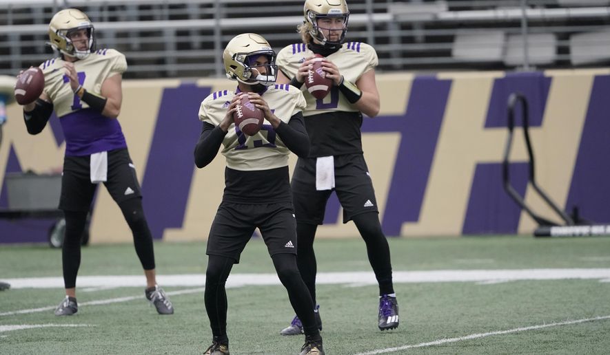 Washington quarterbacks Jaden Sheffey, center, Kevin Thomson, left, and Jacob Sirmon, right, pass in a group during NCAA college football practice, Friday, Oct. 16, 2020, in Seattle. (AP Photo/Ted S. Warren)