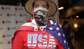 In this Sept. 29, 2020, file photo, Eddie Collantes stands with an American flag draped around his shoulders as he attends a debate watch party hosted by the Miami Young Republicans, Latinos for Trump, and other groups in Miami. (AP Photo/Lynne Sladky, File)