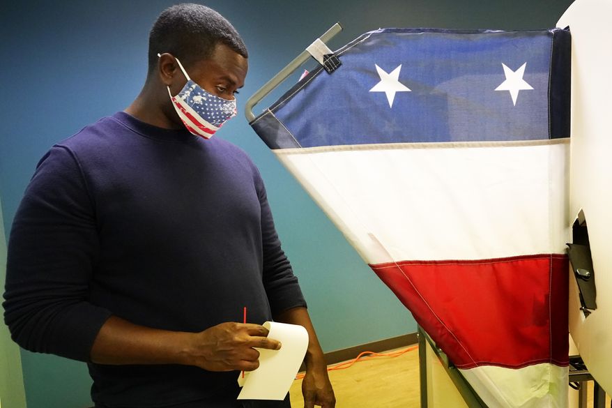 Brian Woodard removes his ballot from a voting booth on the first day of Tennessee's early voting Wednesday, Oct. 14, 2020, in Nashville, Tenn. The early, in-person voting period runs Monday through Saturday until Thursday, Oct. 29. (AP Photo/Mark Humphrey)