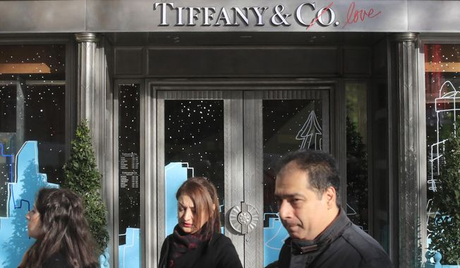 FILE - In this Nov. 25, 2019 file photo, people walk past a Tiffany jeweler shop on the Champs Elysees avenue in Paris. LVMH and Tiffany have worked through their differences, with the famous jewelry company agreeing to be purchased by the luxury goods company for slightly less than what they initially agreed on. (AP Photo/Michel Euler, File)