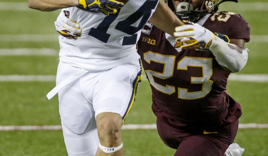 Minnesota defensive back Jordan Howden (23) tackles Michigan wide receiver Roman Wilson (14) on a pass play in the third quarter of an NCAA college football game Saturday, Oct. 24, 2020, in Minneapolis. Michigan won 49-24. (AP Photo/Bruce Kluckhohn)