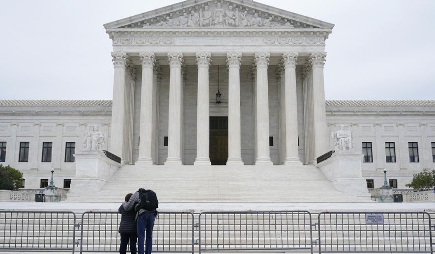 A woman and man pray outside the Supreme Court on Capitol Hill in Washington, Tuesday, Oct. 27, 2020, the day after the Senate confirmed Amy Coney Barrett to become a Supreme Court Justice. (AP Photo/Patrick Semansky)