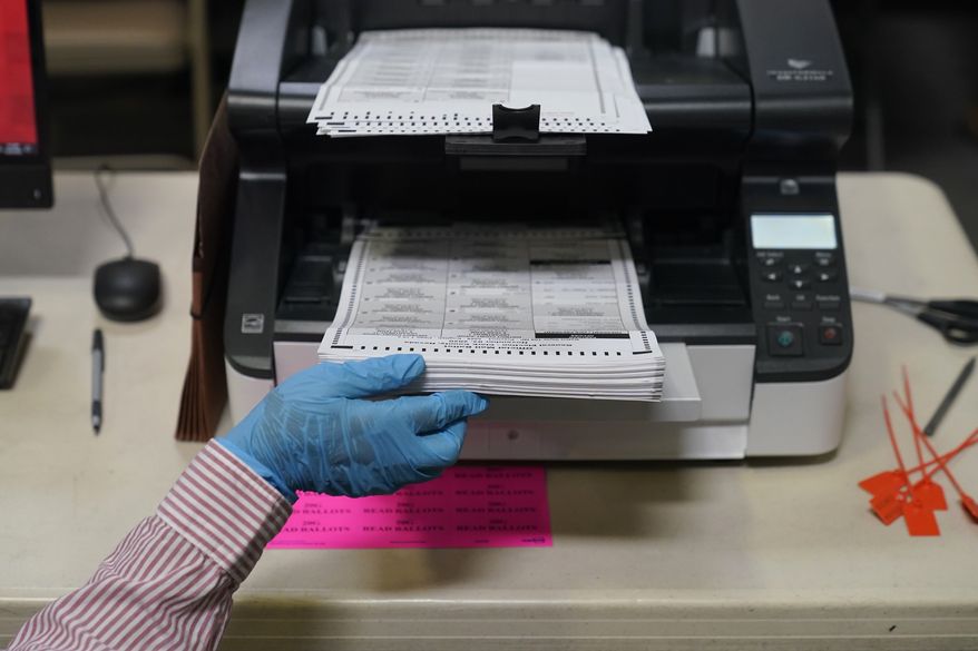 A county worker loads mail-in ballots into a scanner that records the votes at a tabulating area at the Clark County Election Department, Thursday, Oct. 29, 2020, in Las Vegas. (AP Photo/John Locher)