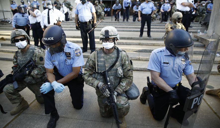 FILE - In this June 1, 2020, file photo, Philadelphia police and Pennsylvania National Guard take a knee at the suggestion of Philadelphia Police Deputy Commissioner Melvin Singleton, unseen, outside Philadelphia Police headquarters in Philadelphia, during a march calling for justice over the death of George Floyd. If the military has any role in next week&#39;s election, it most likely will involve National Guard members under state control — not troops on federal duty.  (AP Photo/Matt Rourke, File)