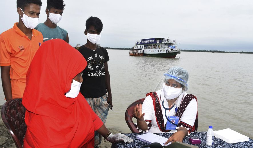 In this photo provided by Bidyanondo Foundation, a doctor examines a patient after arriving at Banishanta village near Mongla seaport in southwestern region of Bangladesh, on Sept. 1, 2020. A Bangladeshi charity has set up a floating hospital turning a small tourist boat into a healthcare facility to provide services to thousands of people affected by this year's devastating floods that marooned millions. (Bidyanondo Foundation via AP)