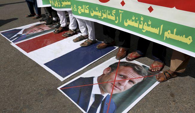 Supporters of the Muslims Students Organization stand on a representation of a French national flag and defaced images of French President Emmanuel Macron during a protest against the president and against the publishing of caricatures of the Prophet Muhammad they deem blasphemous, in Karachi, Pakistan, Friday, Oct. 30, 2020. Muslims have been calling for both protests and a boycott of French goods in response to France&#x27;s stance on caricatures of Islam&#x27;s most revered prophet. (AP Photo/Fareed Khan)
