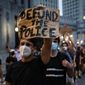 This photo from Thursday, July 30, 2020, shows a demonstrator holding a sign that reads &quot;Defund the police&quot; during a protest march in New York. (AP Photo/John Minchillo) **FILE**